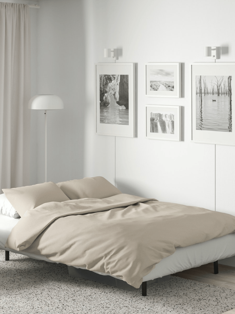 Una cama blanca con ropa de cama beige en una habitación blanca.