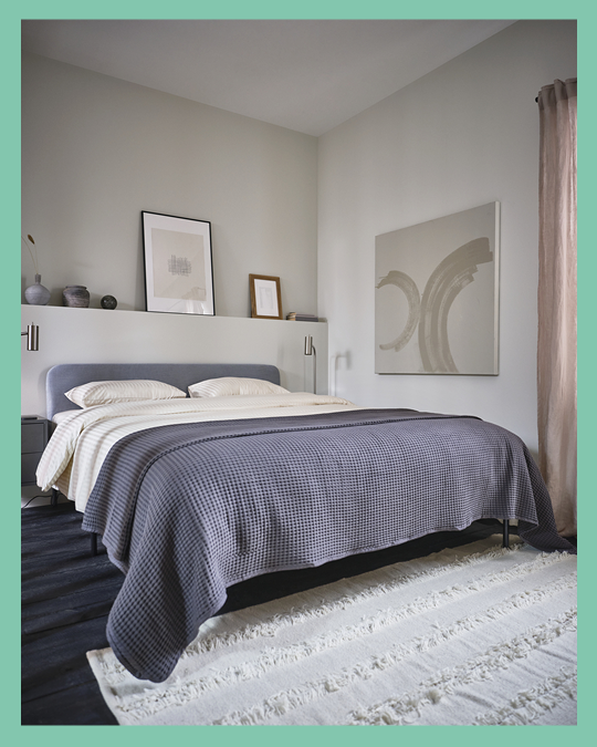 Una cama con cabecero con su ropa de cama y una alfombra en el lado de los pies.