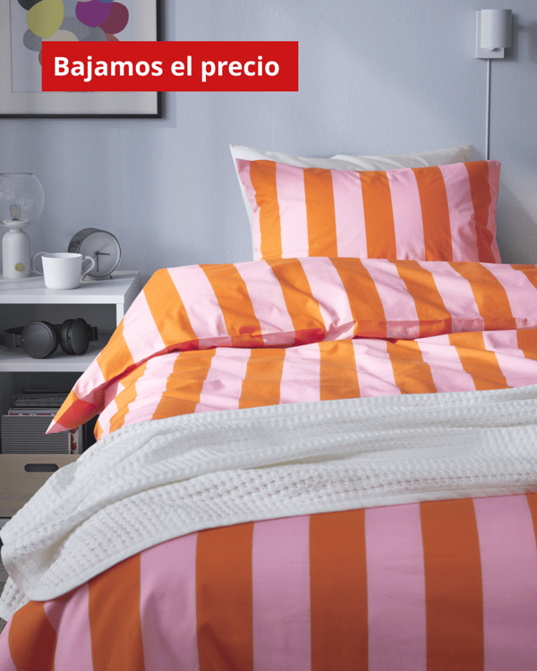 Una cama con ropa de cama a rayas naranjas y rosas. En la parte superior de la imagen una etiqueta que dice "bajamos el precio".
