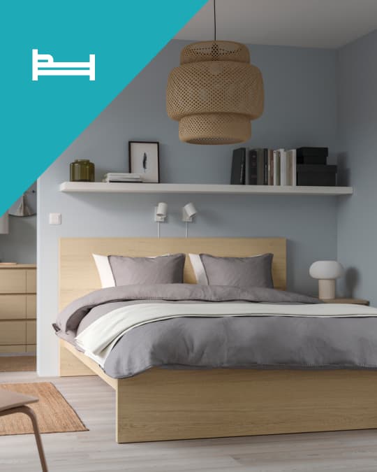 Una cama doble MALM con efecto madera con ropa de cama gris.