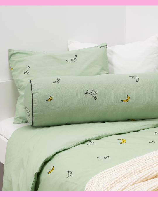 Una cama infantil con ropa de cama con diseño de bananas.