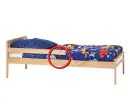 Una cama tamaño twin de madera con un círculo rojo que destaca la barandilla de la cama.