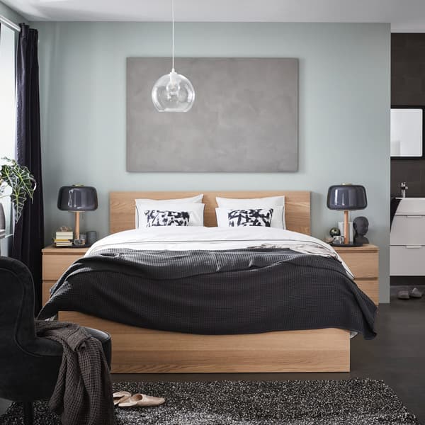 Una camera da letto con al centro un struttura letto alta MALM con due comodini accanto su cui sono appoggiate una lampada da tavolo EVEDAL. Alla parete dietro il letto è appesso un quadro. 
