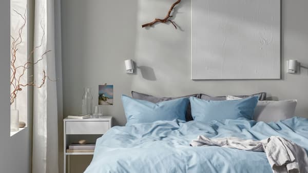 Una camera da letto con comodino e un letto con lenzuola azzurre e grigie. 