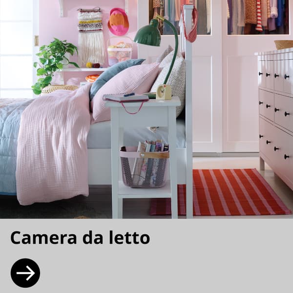 Una camera da letto con mobili bianchi e biancheria colorata.