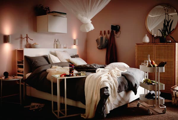 Una camera da letto con una tenda annodata, un carrello bianco RÅSKOG e mobili STOCKHOLM alla parete.