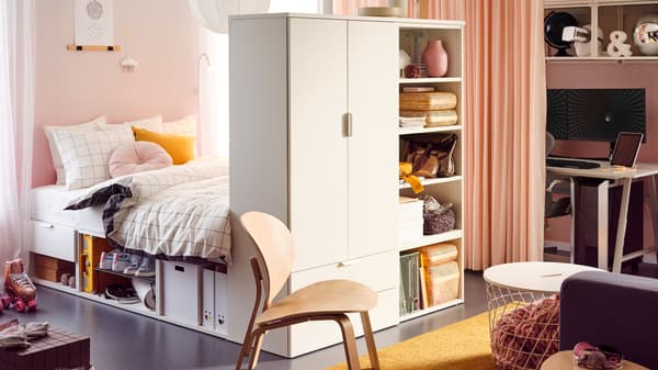 Una camera per teenager con una struttura letto PLATSA con alcuni oggetti e cestini sugli scaffali ai piedi del letto e un tappeto giallo sul pavimento - IKEA