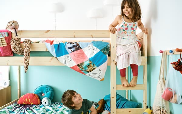 Una cameretta arredata con un letto a castello MYDAL. Un bambino è seduto nel letto di sotto, mentre una bambina è in cima alla scaletta, sul letto superiore - IKEA