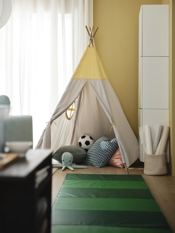 Una cameretta con una tenda HÖVLIG e un tappetino PLUFSIG. All'interno vari peluche e giocattoli.