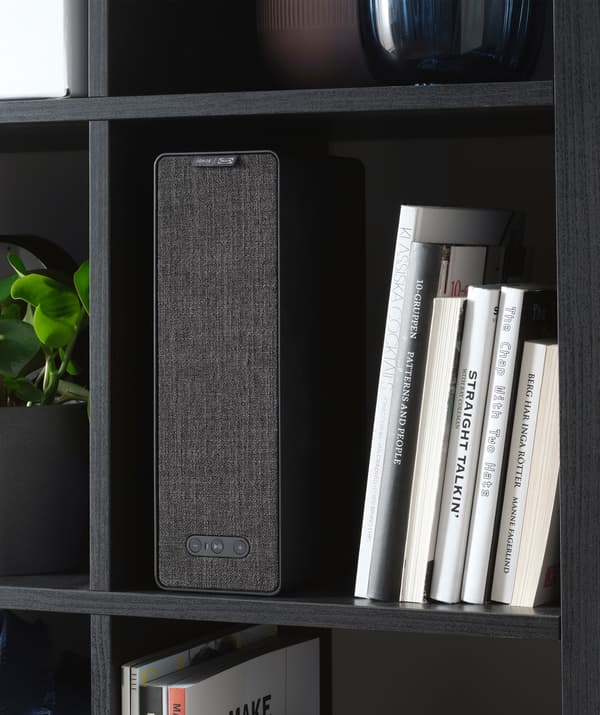 Una cassa rettangolare e dei libri su uno scaffale nero.