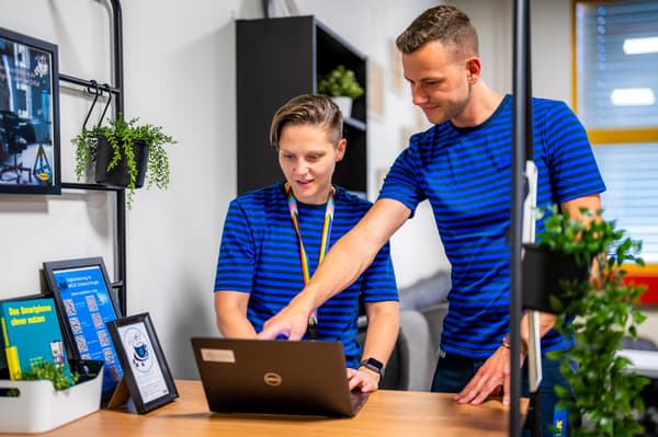 Una cliente IKEA guarda una poltrona STRANDMON gialla sul suo telefono cellulare.