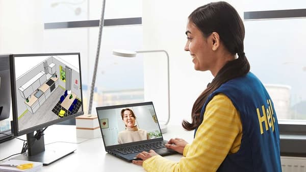 Una co-worker IKEA sorridente in divisa gialla durante una consulenza al computer.