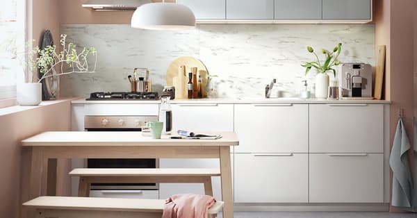 Una cocina blanca con mesa de madera y bancos.