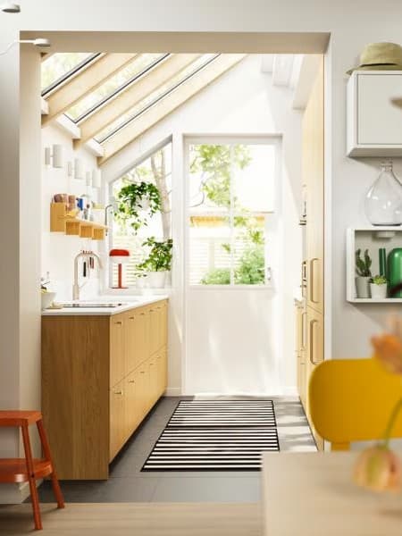 Una cocina con techo abuhardillado con ventanas y una puerta que da al patio, con armarios con frentes SINARP en chapa de roble.