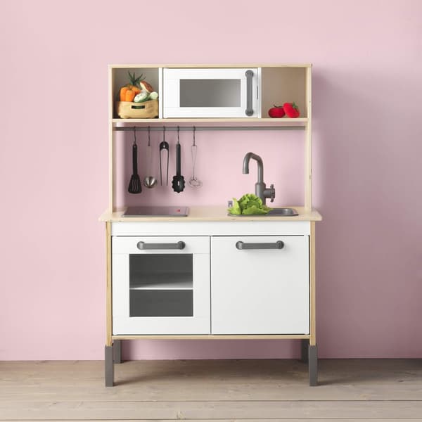 Una cocina de juegos DUKTIG sobre una pared rosa.