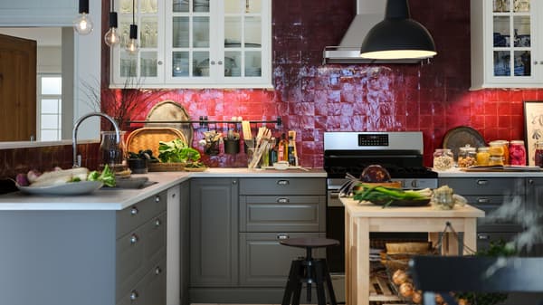 Una cocina SEKTION/MAXIMERA con una barra EKBACKEN y dos carritos de cocina BEKVÄM de abedul que crean una isla de cocina.