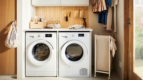 Una combinazione di mobili per lavanderia ENHET con una lavatrice UDDARP, un'asciugatrice UDDARP e vestiti appesi - IKEA.