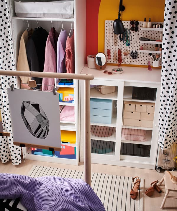 Una combinazione di scaffali e soluzioni a giorno e chiuse lungo una parete e una passerella ricavata tra la tenda e la testiera del letto - IKEA