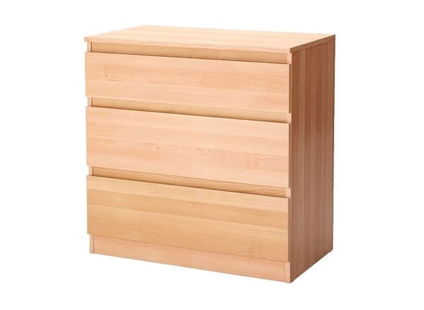 Una cómoda de 3 cajones de color madera clara sobre un fondo blanco