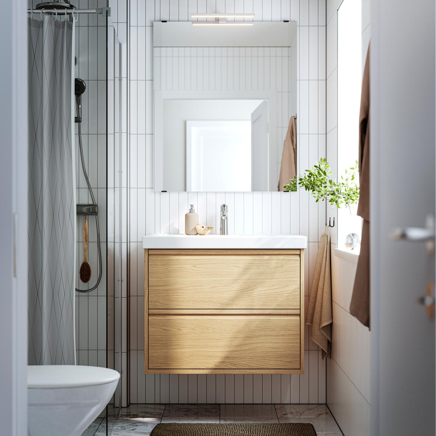 Una composizione bagno ÄNGSJÖN rovere visto frontalmente con specchio rettangolare e accessori per il bagno.