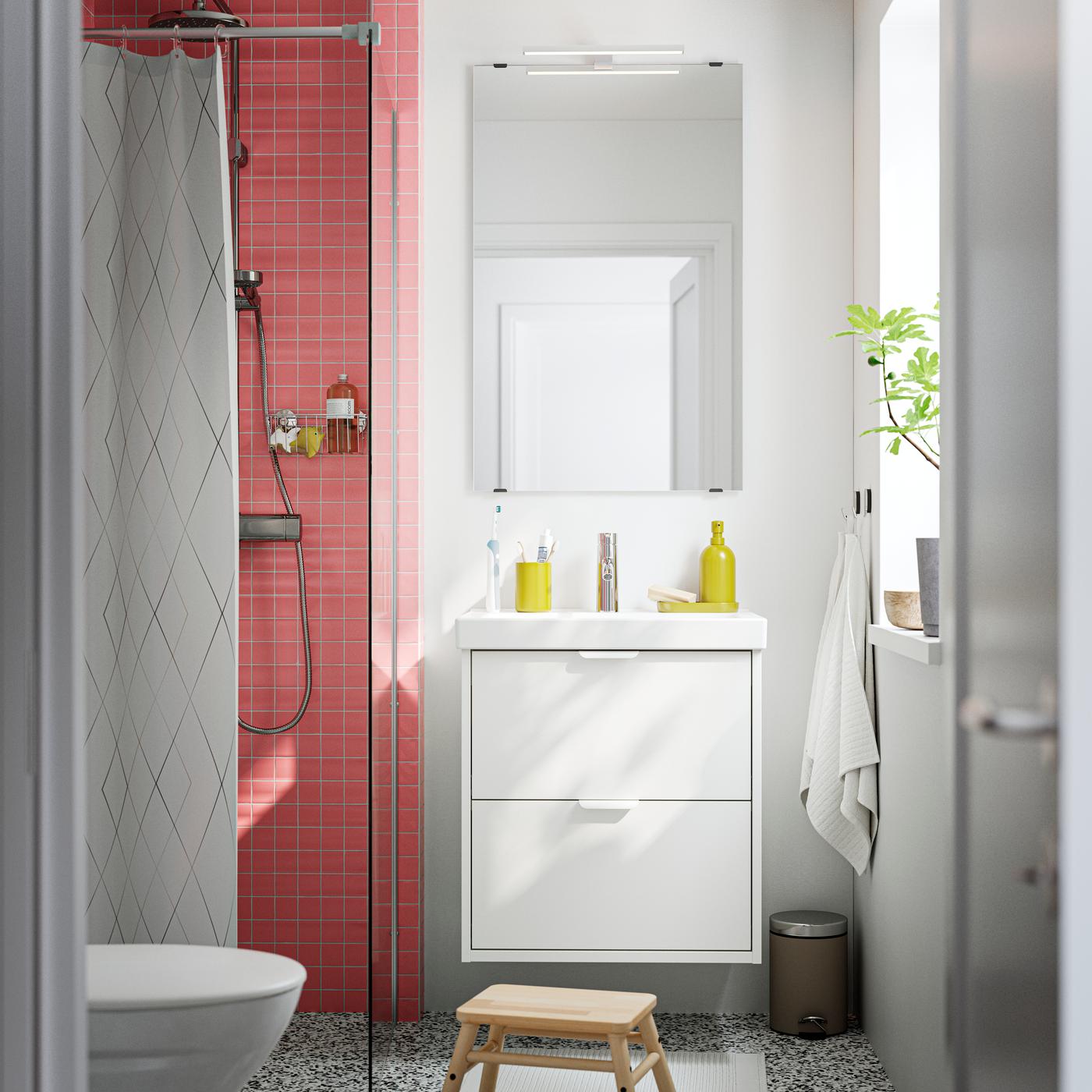 Una composizione bagno HAVBÄCK bianco visto frontalmente con specchio rettangolare e accessori per il bagno.