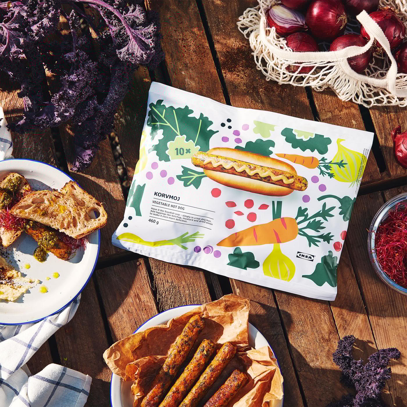 una confezione di hot dog vegetariani KORVMOJ vista dall'alto su un tavolo in legno. Accanto, ci sono altri alimenti e verdure.