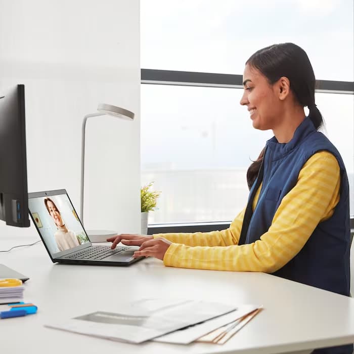 Una consulente di IKEA in divisa in videoconferenza con un cliente a cui mostra un progetto online