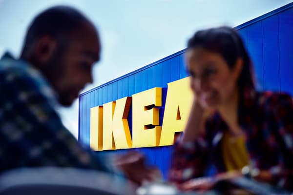 Una conversación entre un hombre y una mujer, donde ambos sonríen y tienen de fondo una tienda IKEA con el logo grande con los colores azul y amarillo.