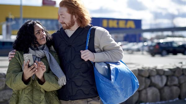 Una coppia è in piedi davanti a un negozio IKEA con una borsa della spesa IKEA blu. 