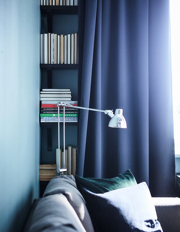 Una cortina blau fosc al davant d’una llibreria en una sala, utilitzada per amagar la solució d’emmagatzematge.