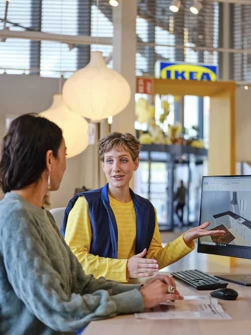 Una coworker IKEA che aiuta una cliente a progettare una cucina.