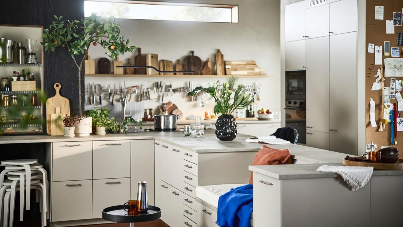 Una cucina angolare di colore bianco con diversi articoli tra cui taglieri, vasi, pentole e altri utensili.