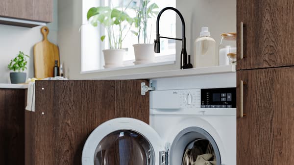 Una cucina con anta marrone aperta, dal quale si vede  una lavatrice integrata alla cucina - IKEA.