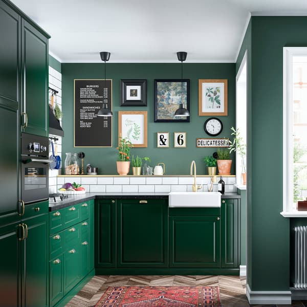 Una cucina con contenitori coordinati per colore, molti piani di lavoro, un fornello e un lavello e alcuni quadri incorniciati alla parete.