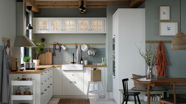Una cucina con frontali cassetto e ante a vetro STENSUND, piani di lavoro effetto rovere e un lavello con frontale visibile bianco - IKEA.