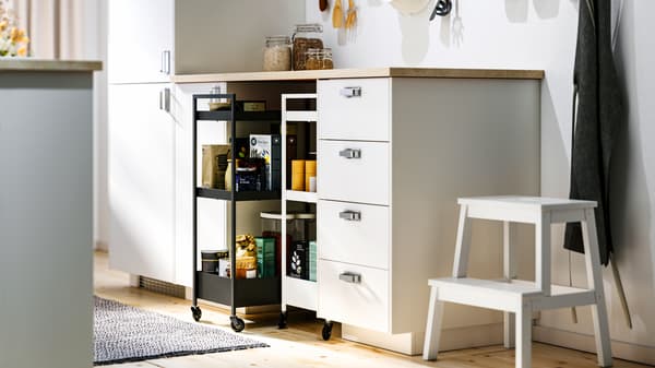 Una cucina con mobili base METOD bianchi e interni MAXIMERA, un piano di lavoro ERBACKEN e due carrelli NISSAFORS - IKEA