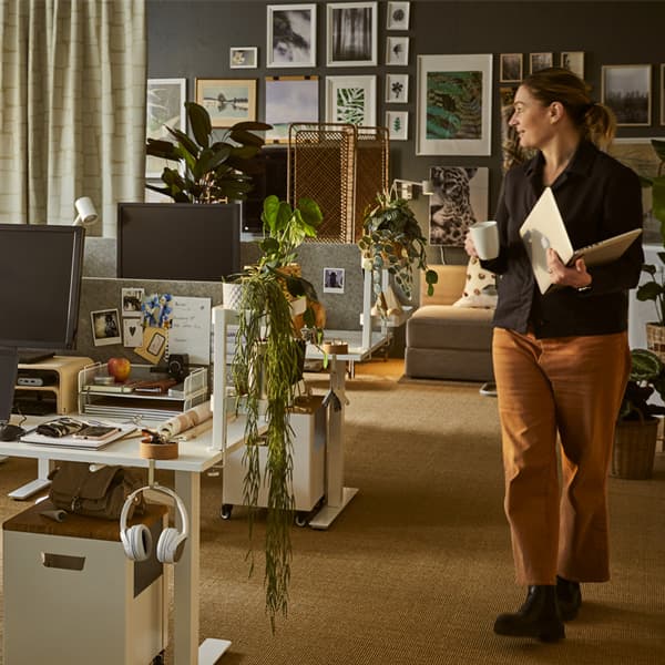 Una donna che cammina in un uffucio arredato con scrivanie, sedie e cassettiere IKEA.