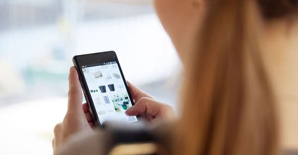 Una donna di spalle che consulta l'app di Ikea tenendo uno smartphone tra le mani.