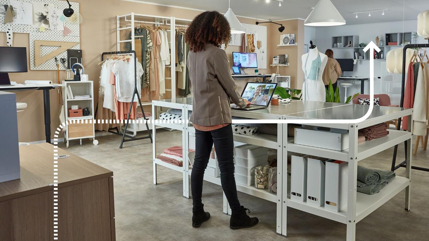 Una donna è in piedi su una scrivania tra i mobili IKEA con il suo computer e ha una videochiamata.