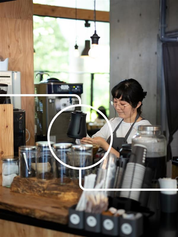 Una donna in piedi dietro il bancone di un bar che prepara un caffè per un cliente