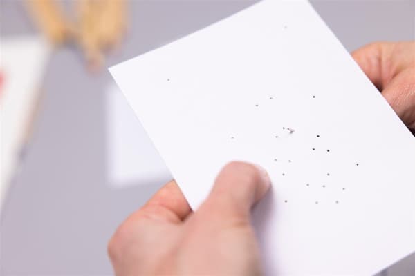 Una donna infila un filo in un foglio di carta