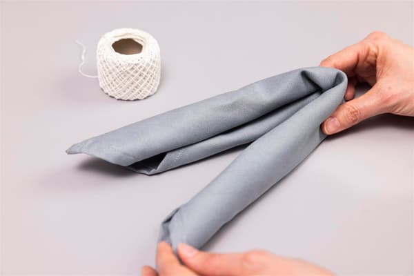 Una donna piega a metà il tovagliolo arrotolato.