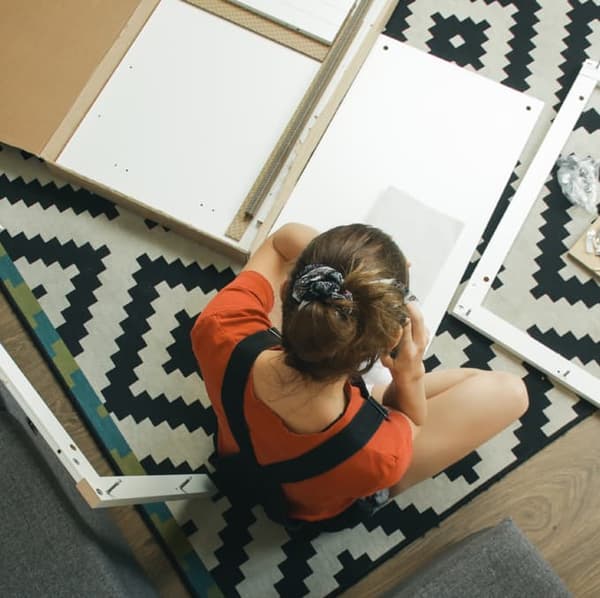 Una donna su un tappeto guarda dei pezzi per il montaggio di un mobile e  accessori interni 