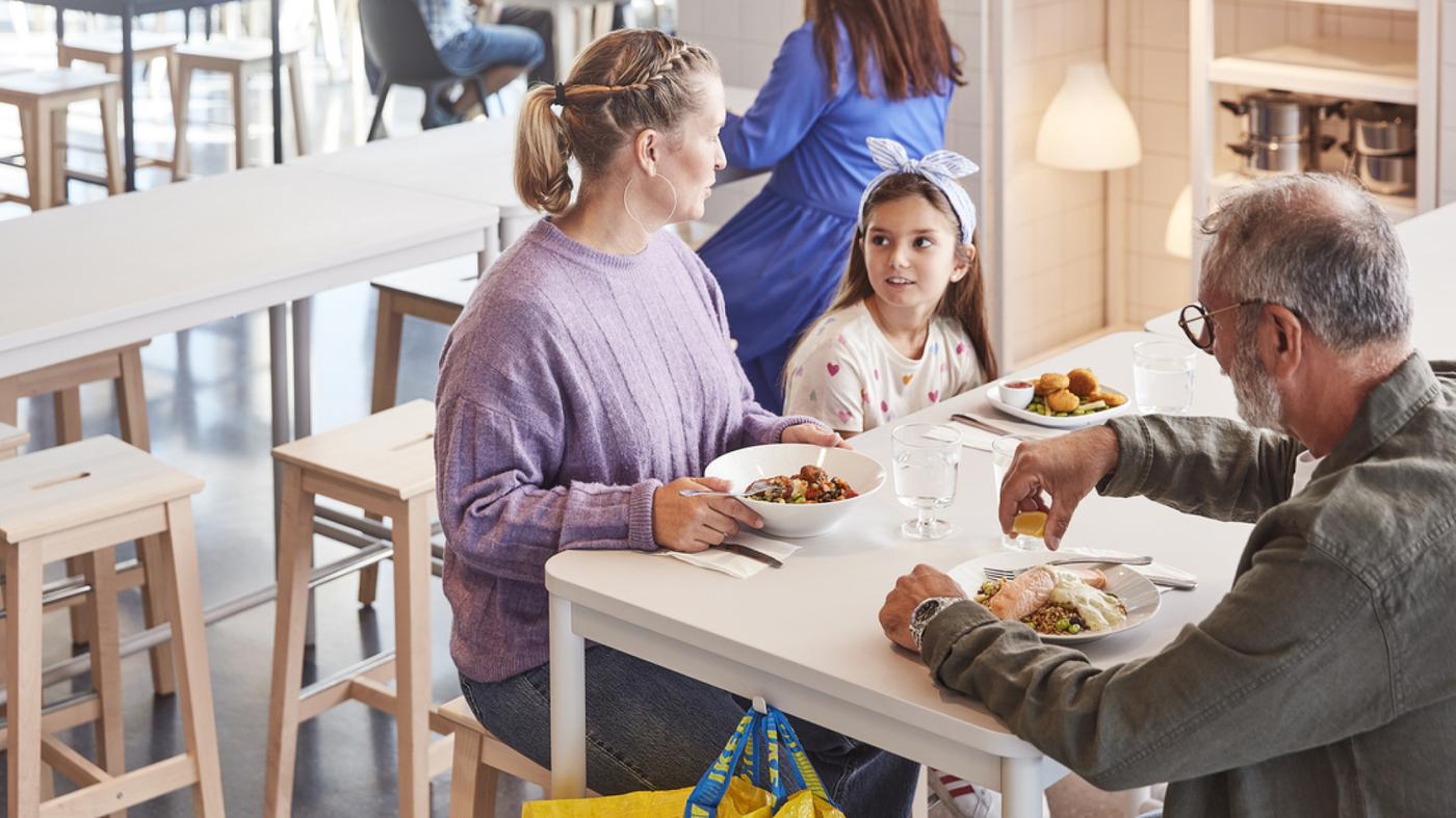Una donna, una bambina e un uomo pranzano in un negozio IKEA.