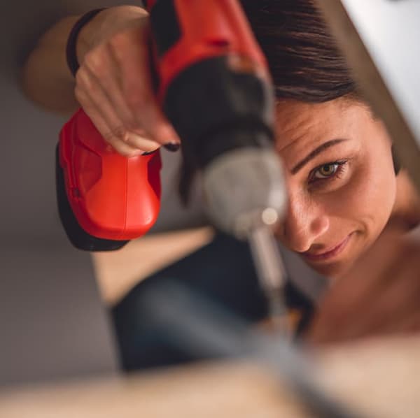 Una donna usa trapano per riparazioni domestiche