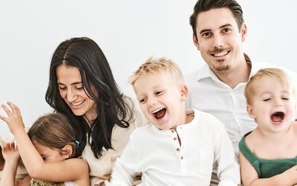 Una famiglia di cinque persone ride insieme.