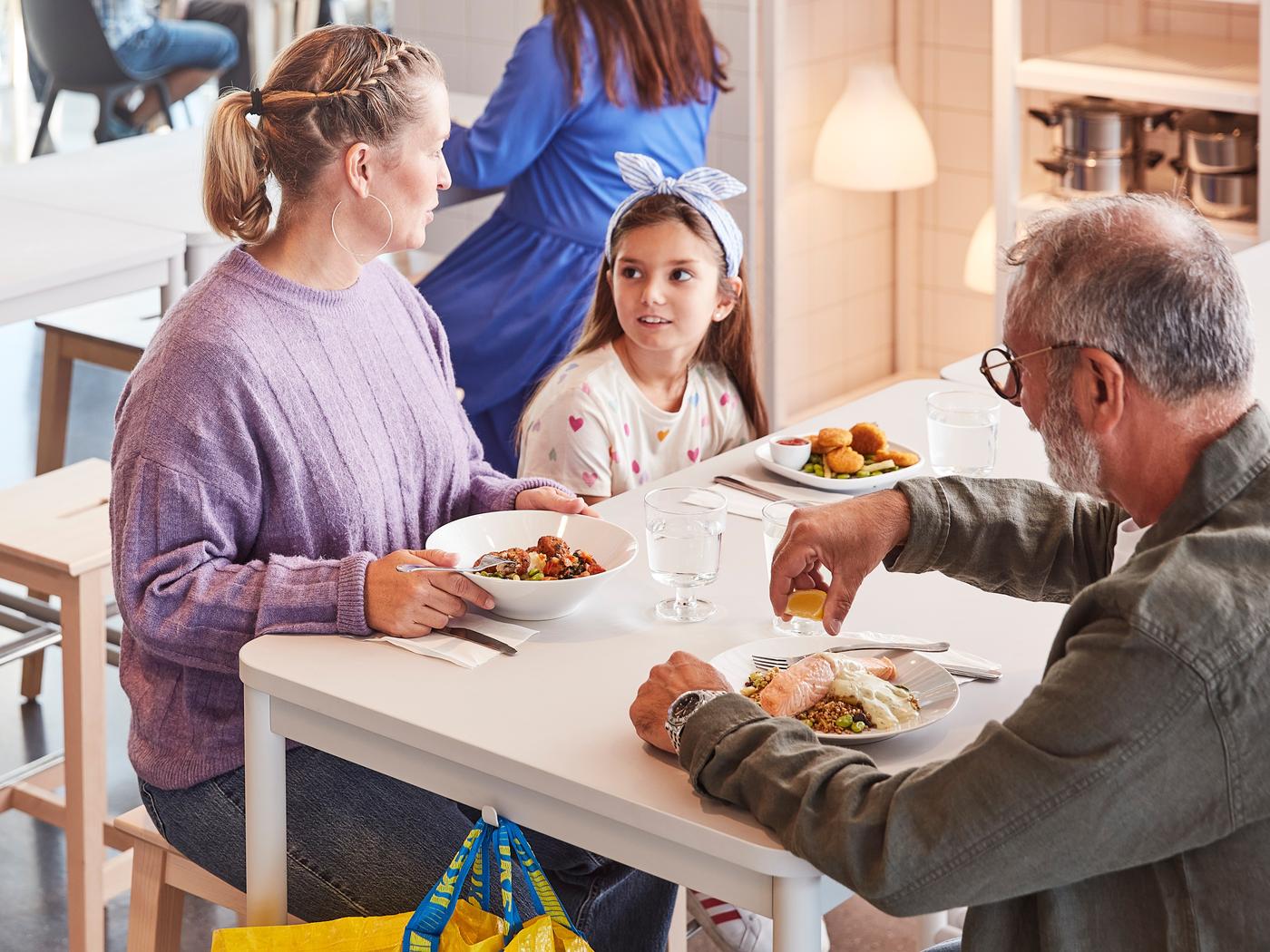 Una familia de tres comiendo en una tienda IKEA.