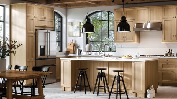 Una gran cocina luminosa con frentes de roble VEDHAMN y una isla de cocina con dos lámparas de techo encima y bancos altos al frente.
