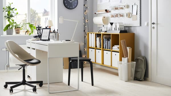 Una habitacion con un escritorio MICKE blanco de dos cajones y muebles de oficina.