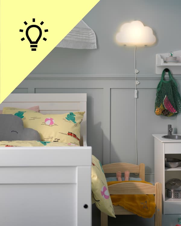Una habitación infantilcon una lámpara en forma de nube encendida al costado de la cama y en la esquina superior izquierda de la foto un triángulo amarillo con un ícono de ampolleta.